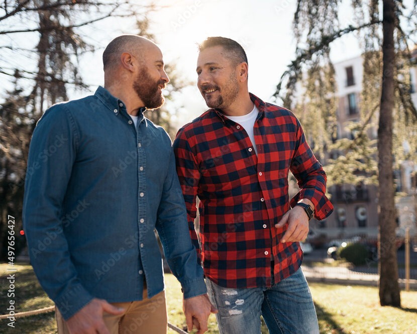 Two men smiling at each other holding hands.